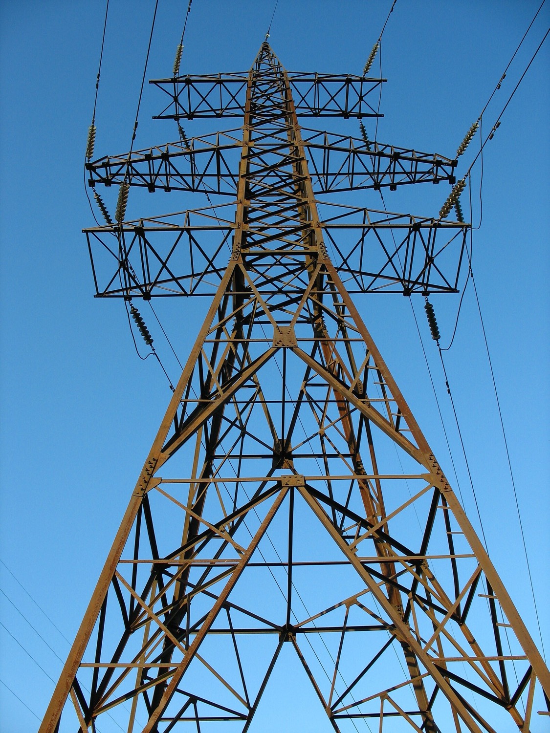 A high-voltage transmission tower against a blue sky